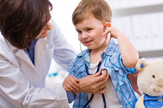 Image of doctor helping a little boy listen to his own heartbeat with a stethescope.